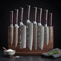 Set of japanese damascus chef knives with wooden handles on a wooden block against a black background. SteelSensei Takasu
